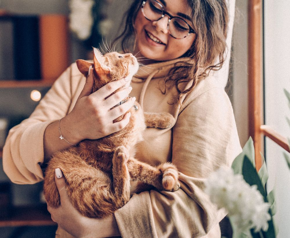 A person wearing glasses and a beige hoodie cat